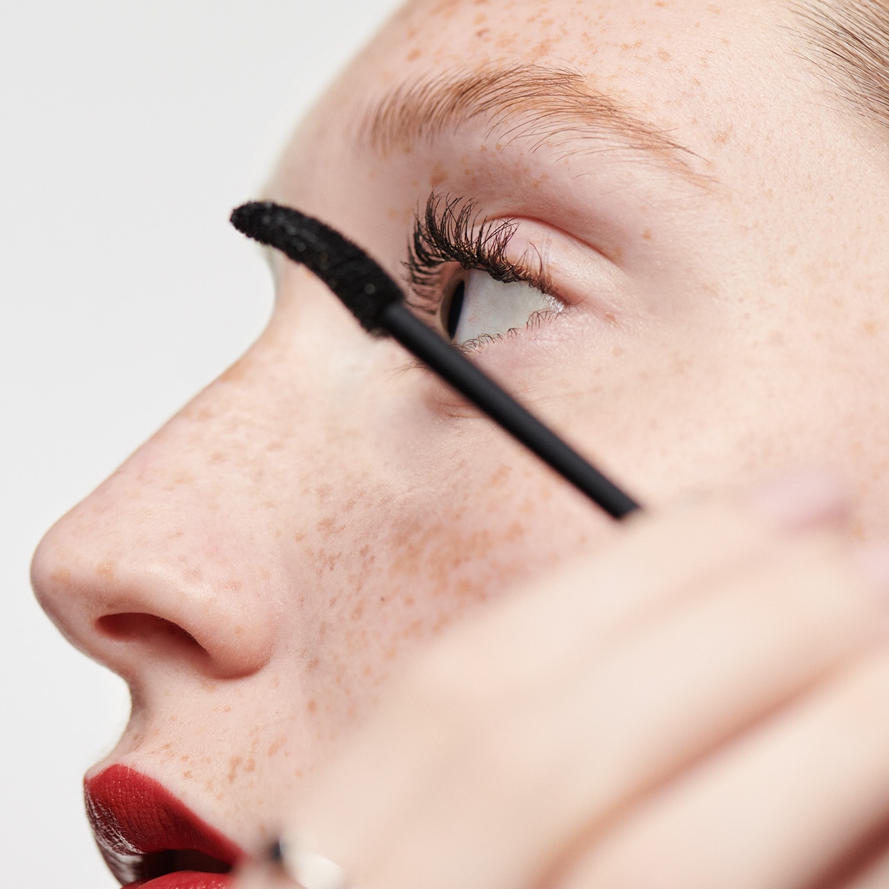 Close up of model applying mascara to eye lashes