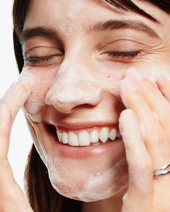 Close up of model applying Moisture Surge Serum to skin, focusing on product texture