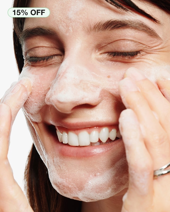 Close up of brunette model, smiling and she cleanses her skin