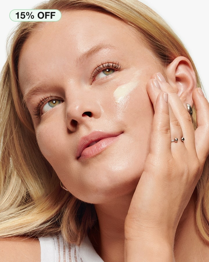 Close up of blonde model applying Clinique Pop Lip + Cheek Oil in Black Honey to cheeks