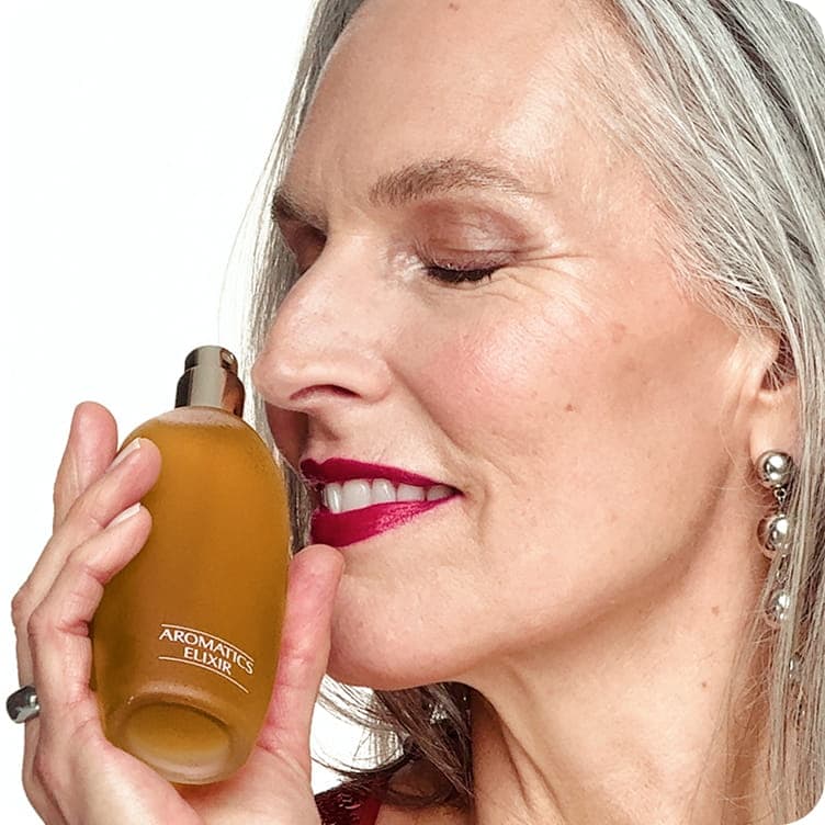 Woman with gray hair smelling Clinique perfume 