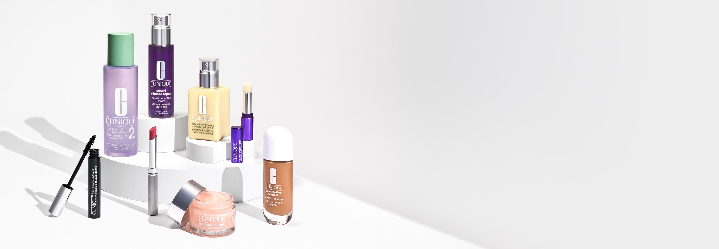 Selection of bestselling Clinique skincare and makeup products, on a grey podium, in a brightly lit studio setting